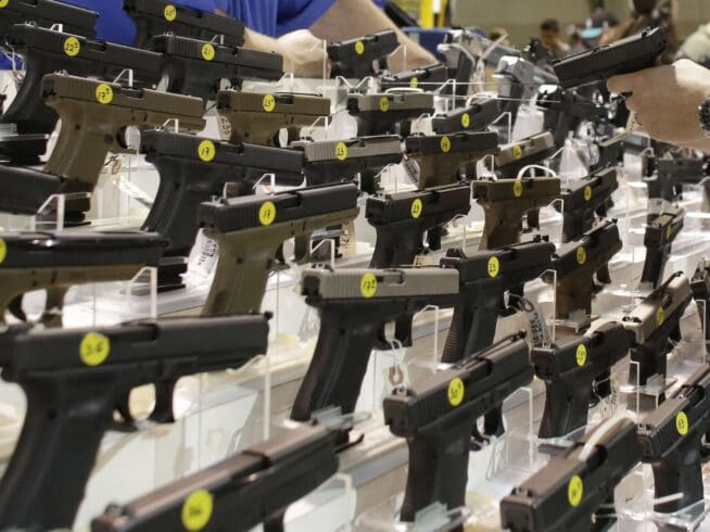 A customer looks at a pistol at a vendor's display at a gun show held by Florida Gun Shows in Miami on Saturday, Jan. 9, 2016. (AP Photo/Lynne Sladky)