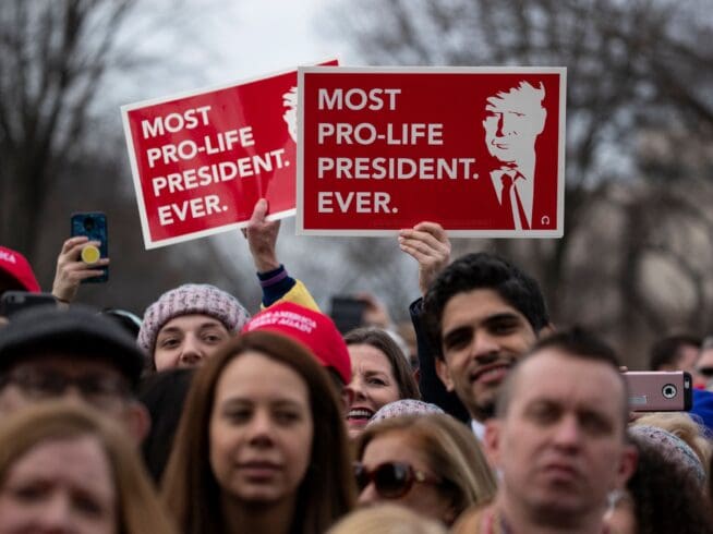 Supporters listen and hold up signs as President Donald Trump speaks during the annual "March for Life" rally on the National Mall, Friday, Jan. 24, 2020, in Washington.