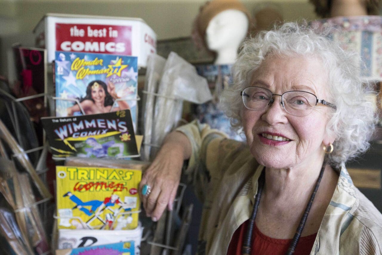 Cartoonist Trina Robbins poses next to a display of her work.