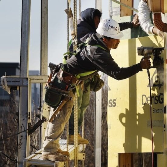 Workers apply sheathing to the exterior of a new multifamily residential building, Friday, Nov. 3, 2023, in the East Boston neighborhood of Boston. (AP Photo/Michael Dwyer)